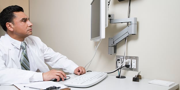doctor looking up at a monitor and typing