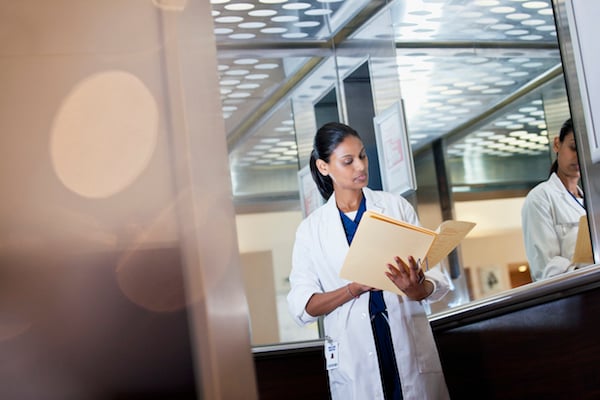 minority female doctor doctor reviewing a medical record in a hospital elevator